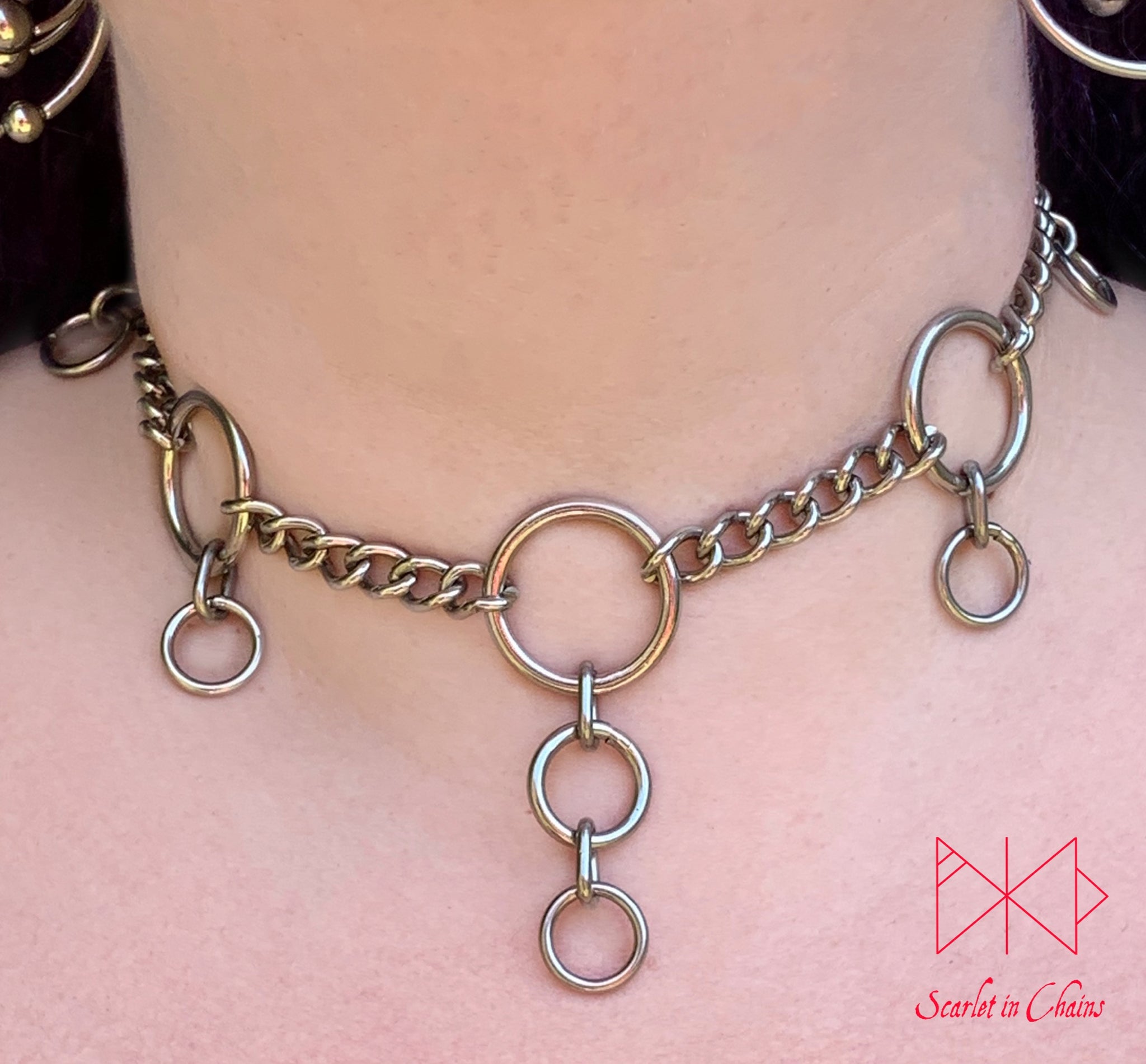Coven mini collar worn, Stainless steel mini chain choker with 5 o rings spaced around the collar with a smaller o ring hanging from the side ones and 2 smaller o rings hanging from the central one with new links