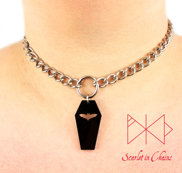 Coffin choker shown on model. Stainless Steel chain choker with stainless steel O ring at it centre. With a black perspex coffin pendant with a bat cut out suspended from the ring.