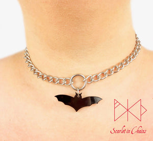 Bat choker worn by model. Stainless steel chain choker with stainless steel o ring at its centre with a black perspex bat pendant hung from the O ring
