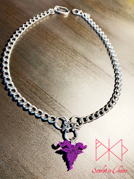 Baphomet choker necklace in purple. A stainless steel chain choker necklace with 3 stainless steel O rings forming an inverted triangle. Hanging from the inverted triangle of O rings is a purple perspex Baphomet pendant with hand finished black facial details. Necklace is closed with an easy to us stainless steel clasp. Shown flat   Edit alt text